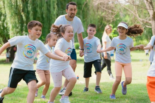 Children joyfully running and holding hands in a sunny park, enjoying outdoor recreation.